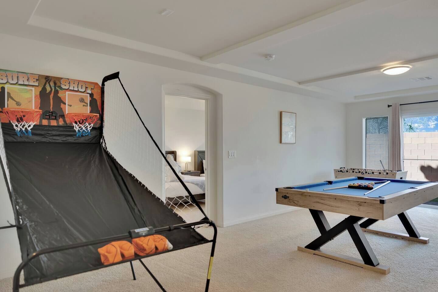 Una habitación con mesa de billar, mesa de fútbol de mesa y aro de baloncesto.