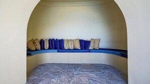 A room with a bed under an arched ceiling, a blue bench with cushions, and a stone-patterned mattress. - 16th-Floor Oceanfront Condo with Stunning Sunset Views (Playas de Rosarito)