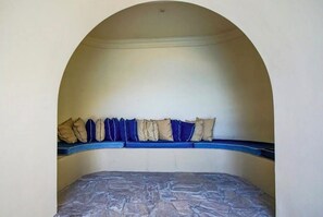 A room with a bed under an arched ceiling, a blue bench with cushions, and a stone-patterned mattress. - 16th-Floor Oceanfront Condo with Stunning Sunset Views (Playas de Rosarito)
