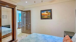A bedroom with a bed, a door, a painting, and a ceiling fan. - 16th-Floor Oceanfront Condo with Stunning Sunset Views (Playas de Rosarito)