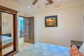 A bedroom with a bed, a door, a painting, and a ceiling fan. - 16th-Floor Oceanfront Condo with Stunning Sunset Views (Playas de Rosarito)