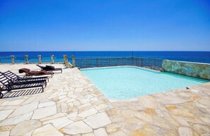 A swimming pool with stone flooring and a view of the ocean. - 16th-Floor Oceanfront Condo with Stunning Sunset Views (Playas de Rosarito)