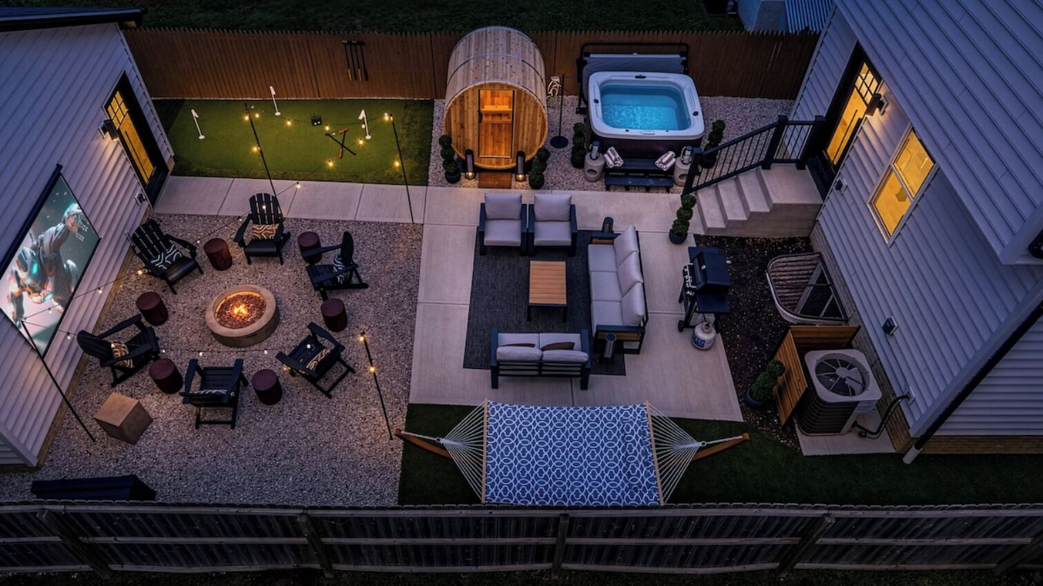 A backyard with a fire pit, outdoor seating, a hot tub, and a hammock.