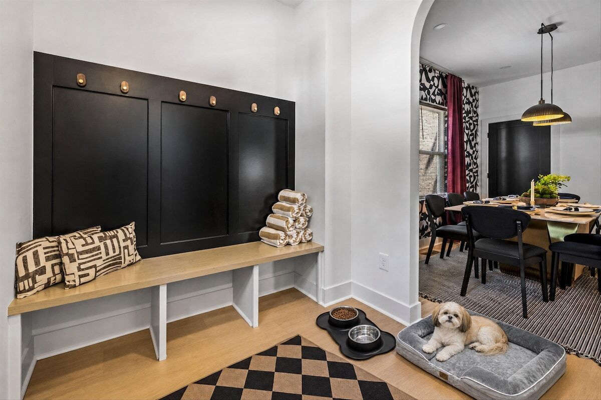 A modern interior with a bench, a dog bed, and a dining area with chairs and a table.