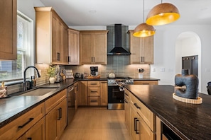 Une cuisine moderne avec des meubles en bois, des appareils électroménagers en acier inoxydable et des luminaires suspendus.