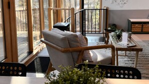 Ett modernt vardagsrum med ett stort fönster, en soffa, ett soffbord och utsikt över en träveranda.