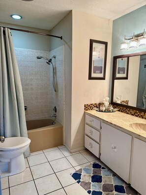 Een badkamer met een bad, toilet en douche.