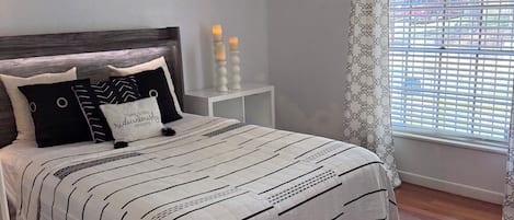 A neatly arranged bedroom with a bed, bedside tables, and a window with curtains.