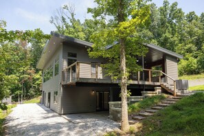 Een huis met twee verdiepingen, een balkon en een trap naar een terras.