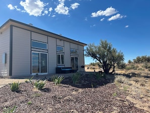 A modern two-story house with large windows and a patio area. - Brand-New 2BR Desert Retreat - Mountain Views & Stargazing (Kingman)
