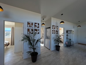 A spacious hallway with a modern design, featuring a potted plant, a white washing machine, and artwork on the walls.