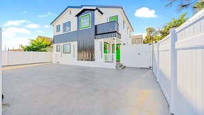 Une maison moderne à deux étages, dotée d’un toit plat, d’un balcon et d’un garage.
