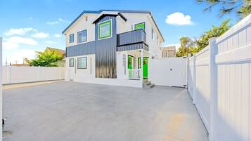 Une maison moderne à deux étages, dotée d’un toit plat, d’un balcon et d’un garage.