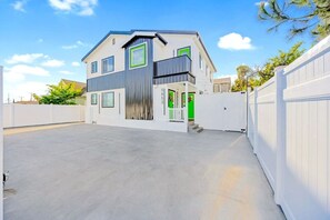 A modern two-story house with a flat roof, a balcony, and a garage.