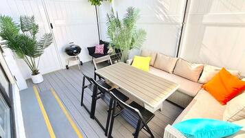 Un espace patio aménagé avec une table et des chaises, un canapé avec des coussins et des plantes en pot.