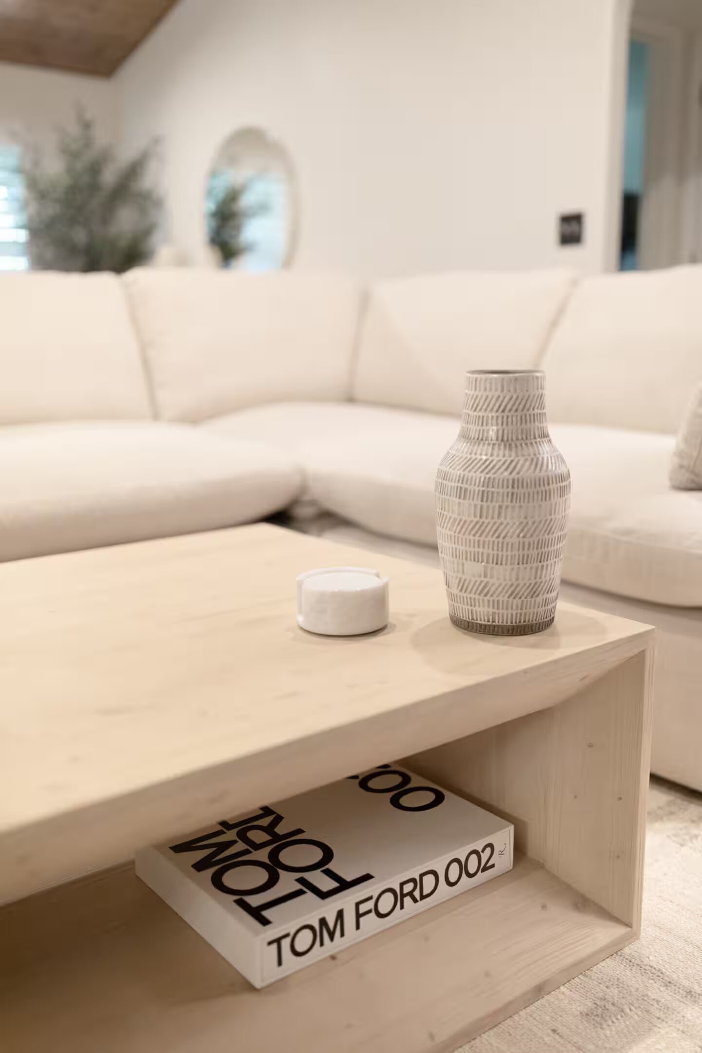A modern living room with a white sofa, a wooden coffee table, and a decorative vase.
