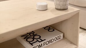 A modern living room with a white sofa, a wooden coffee table, and a decorative vase.