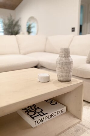 A modern living room with a white sofa, a wooden coffee table, and a decorative vase.