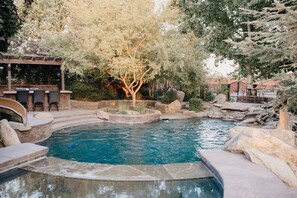 A swimming pool with a hot tub, surrounded by rocks and trees, with outdoor seating and a pergola. - Rustic Chateau/Estate -Pool, Spa, Tennis Court, and Quiet, Peaceful Surroundings (Del Rey)