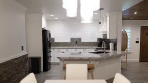 A modern kitchen with a central island, white cabinetry, and a dining area with a table and chairs.