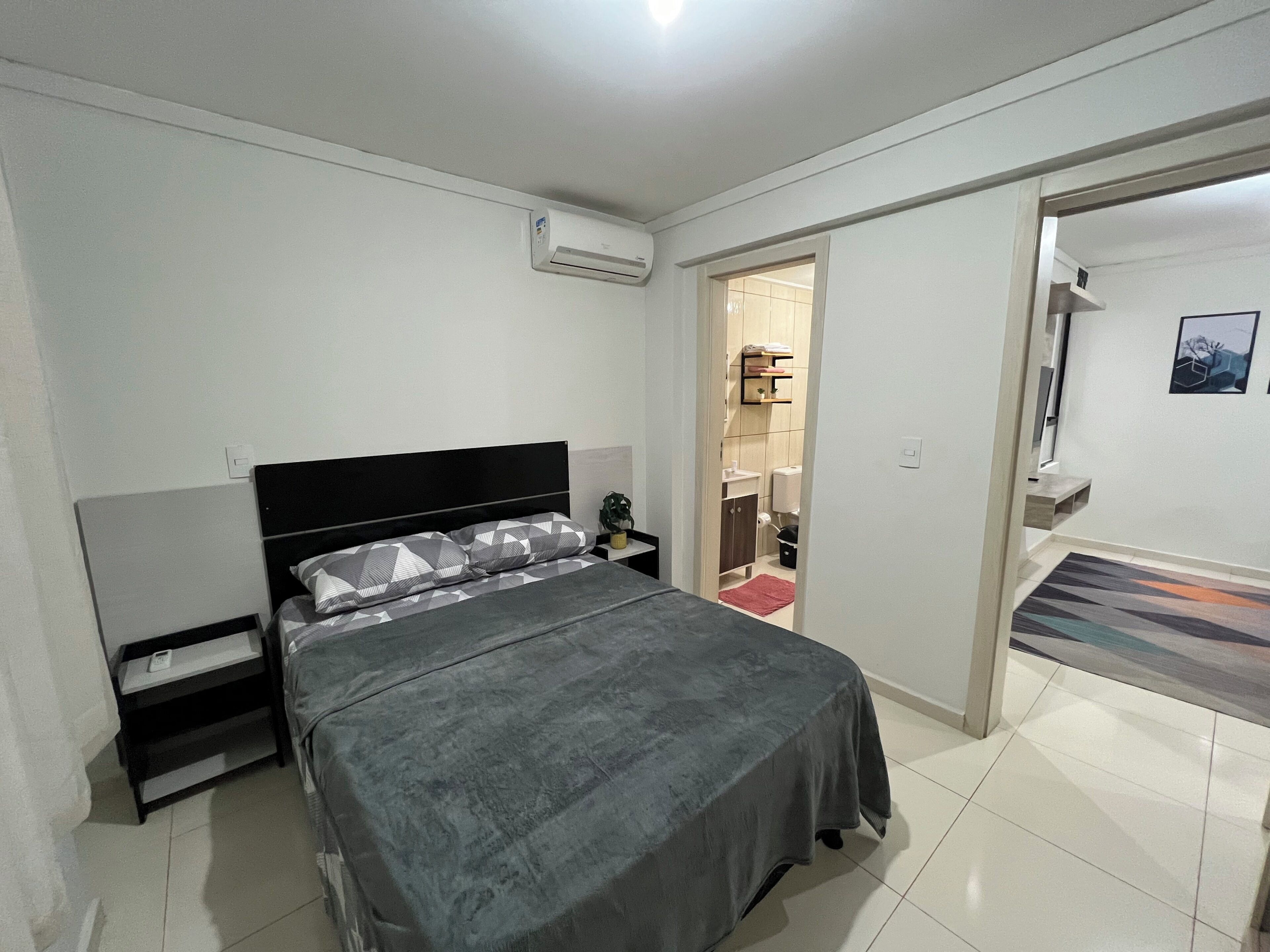A bedroom with a bed, bedside table, and an air conditioning unit.