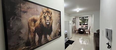 Un pasillo con un cuadro grande de un león, una zona de comedor y un refrigerador.