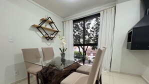 A dining area with a glass table, four chairs, a wooden side table, and a view through a window. - Family apartment with great comfort and a great location in Toledo, Paraná. (Toledo)