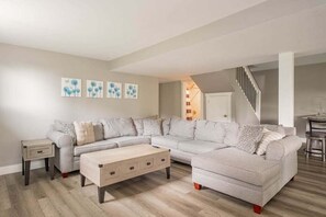 Ein modernes Wohnzimmer mit einem Ecksofa, einem Couchtisch und Kunstwerken an der Wand.