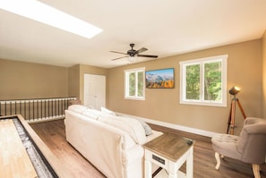 A room with a ceiling fan, a sofa, a small table, a lamp, and a painting on the wall. - Thanksgiving-ready 5BR retreat in Oakland with hot tub (Oakland)