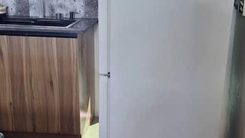 Una cocina con un refrigerador blanco, una encimera de madera y un ventanal con vistas a una cerca verde.