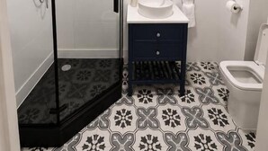 Un baño con cabina de ducha, lavamanos e inodoro.