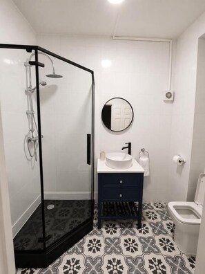 A bathroom with a shower enclosure, a sink, and a toilet.