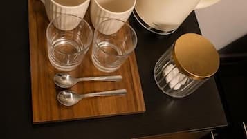 Una encimera de cocina con una bandeja de madera que contiene dos tazas, dos vasos y dos cucharas.