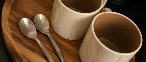 Una bandeja de madera con dos tazas blancas de cerámica y dos cucharas sobre una encimera de cocina.