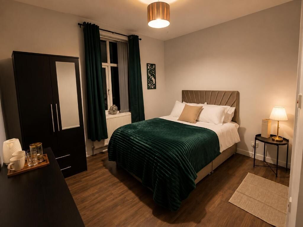 A bedroom with a bed, bedside table, lamp, and a window with curtains.