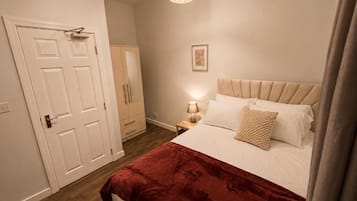 Un dormitorio con cama, mesita de noche, lámpara, puerta y armario.