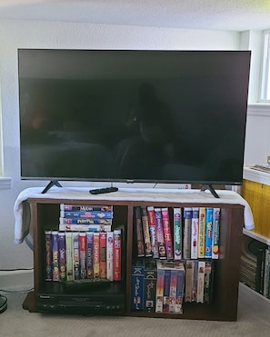 A television on a stand with a shelf of books in front.