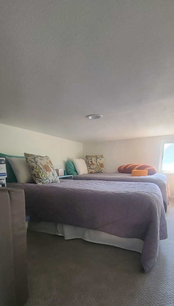 A hotel room with a bed, pillows, a bedside table, and a window.