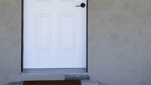 A white door with a black frame, a doorknob, and a mail slot on the wall to the right.
