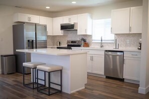 A modern kitchen with white cabinets, a stainless steel refrigerator, a microwave, and a dishwasher. - Spacious 3-bedroom house in serene Clovis with AC (Clovis)
