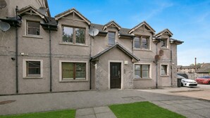 A two-story house with a front door, multiple windows, and satellite dishes. - Leslie Lodge - Grampian Lettings (Inverurie)