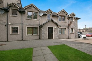 A two-story house with a front door, multiple windows, and satellite dishes. - Leslie Lodge - Grampian Lettings (Inverurie)