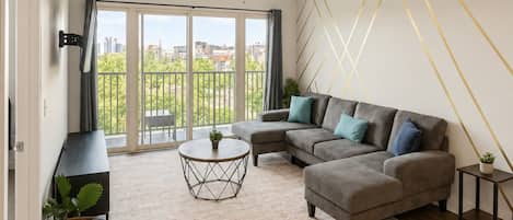 A modern living room with a sectional sofa, a round coffee table, and a ceiling fan.