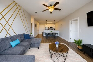 A modern living room with a sectional sofa, a round coffee table, and a ceiling fan. - Stylish 2BR | Balcony + UAB Access (Birmingham)