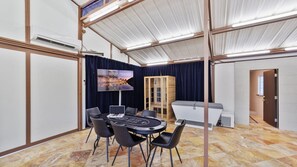 A conference room with a round table, chairs, a large screen, and a sauna.