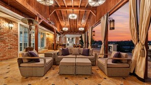 A covered outdoor seating area with wicker furniture and a brick wall. - Private Ranch- Pool, Sauna, Outdoor Theater, & Gaming Barn (El Cajon)
