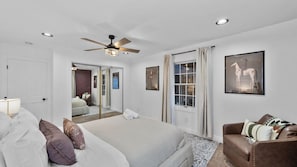 A bedroom with a bed, a ceiling fan, a window with curtains, and a framed picture on the wall.