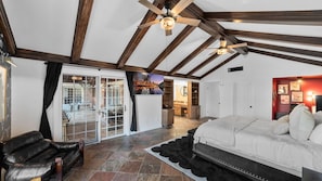 A spacious room with a large bed, a leather sofa, and a sliding glass door leading to an outdoor area. - Private Ranch- Pool, Sauna, Outdoor Theater, & Gaming Barn (El Cajon)