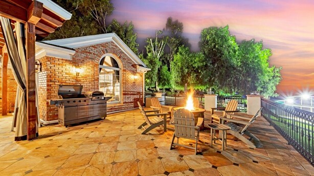 Un patio al aire libre con una zona de barbacoa de ladrillo, asientos y un hogar para fuego.