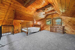 A bedroom with a wooden ceiling, a bed, a dresser, and a window with a view of trees. - Eagle's Landing | Cozy, Pet-Friendly Getaway (Hammondsport)